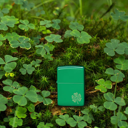 Lifestyle image of Zippo Lucky Clover Design Grass Green Matte Windproof Lighter standing in a bed of clover with some twigs and leaves.
