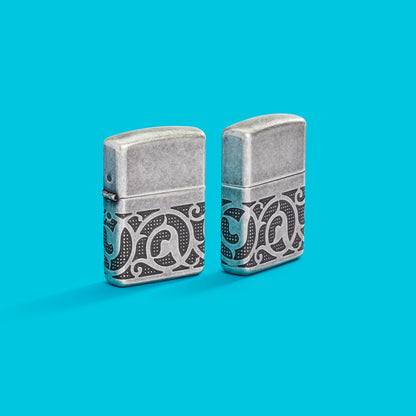 Lifestyle image of two Zippo Pattern Armor Antique Silver Windproof Lighters on an aqua blue background.